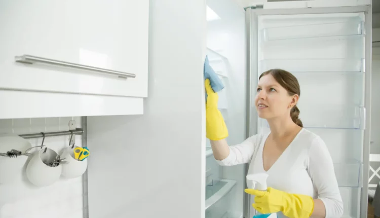 Mulher limpando a geladeira.